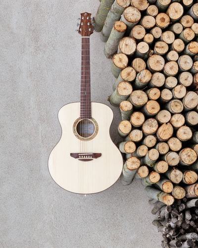 棕色原声吉他靠近一堆木头